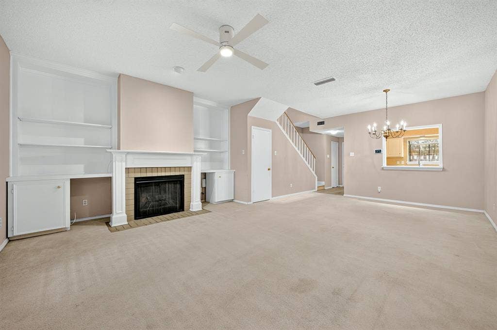 5859 Frankford Road, #1209, Dallas, TX 75252 Fireplace with tiled surround, built-in shelving, ceiling fan, and chandelier fixture