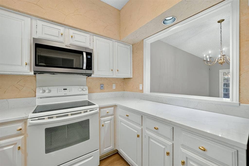 5859 Frankford Road, #1209, Dallas, TX 75252 Kitchen featuring white cabinetry with gold-tone hardware, stone-finish countertops, and stainless steel microwave