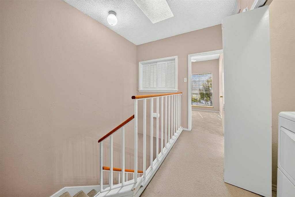 5859 Frankford Road, #1209, Dallas, TX 75252 Staircase featuring a white metal railing with a wood-finish handrail, window with plantation-style shutters, and flush-mount ceiling lighting