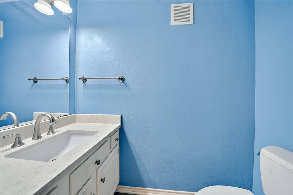 5859 Frankford Road, #1209, Dallas, TX 75252 Bathroom featuring a vanity with a stone countertop, an integrated rectangular sink, a polished metal faucet, a full-width wall mirror, and dual light fixtures