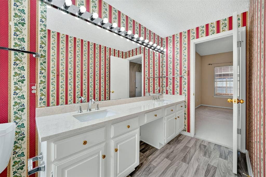 5859 Frankford Road, #1209, Dallas, TX 75252 Bathroom vanity featuring a light-toned countertop, dual integrated sinks, white cabinetry, a full-width wall mirror, and wood-finish flooring