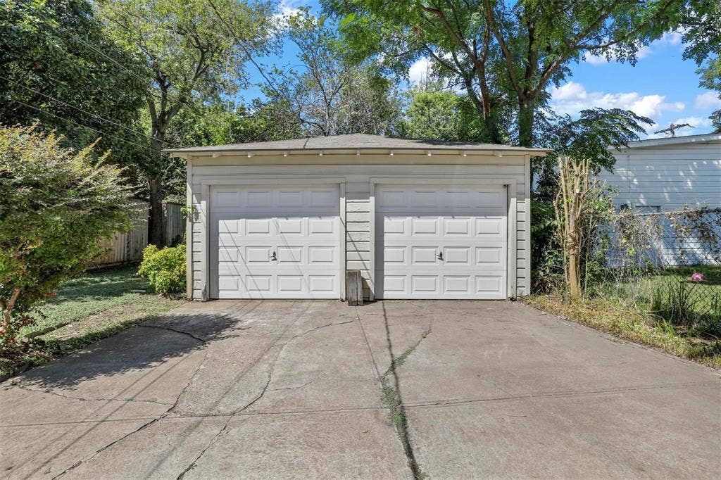 5925 Victor Street, Dallas, TX 75214 Detached two-car garage featuring horizontal siding, a low-pitched roof, and dual paneled overhead doors with a concrete driveway