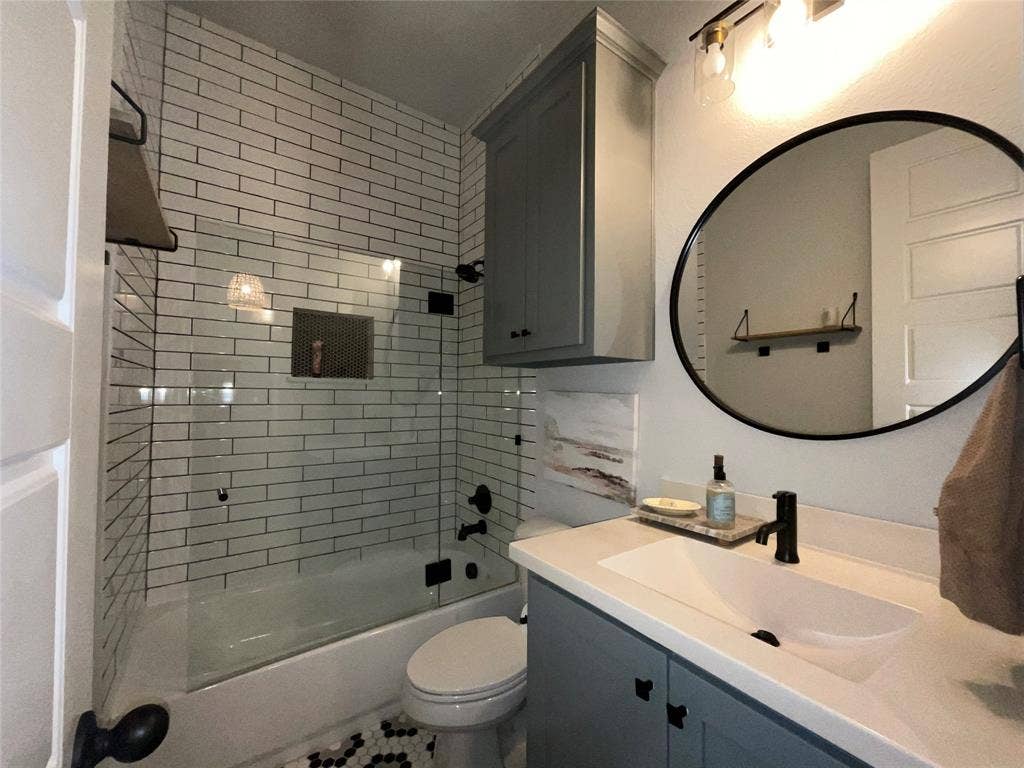 2712 War Admiral Street, Celina, TX 75009 Bathroom featuring subway tile shower surround, glass enclosure, slate-colored cabinetry, solid-surface vanity countertop, and matte black fixtures