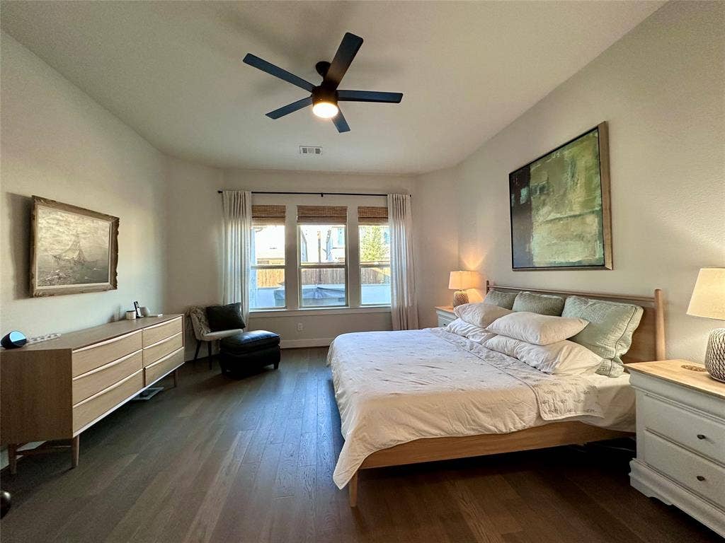 2712 War Admiral Street, Celina, TX 75009 Spacious interior featuring wood-finish flooring, a matte black multi-blade ceiling fan, and three panel windows with integrated hardware