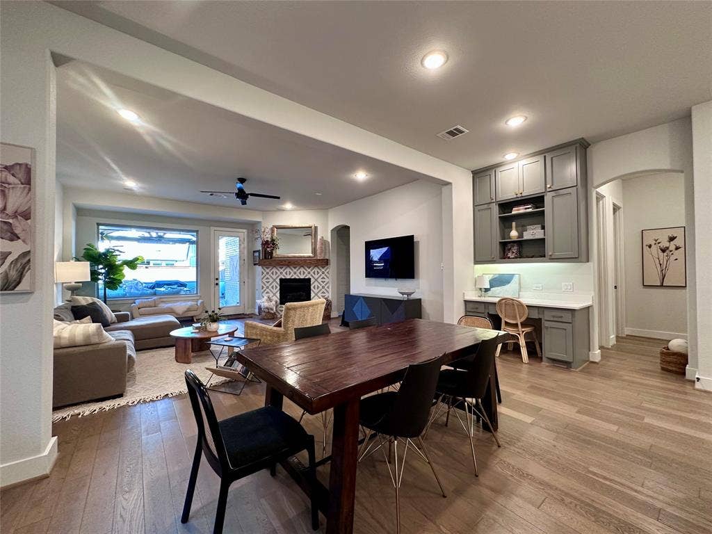 2712 War Admiral Street, Celina, TX 75009 Open-concept interior featuring wood-finish flooring, recessed lighting, a built-in office workstation with overhead cabinetry, and a fireplace with a patterned tile surround and a wood mantel