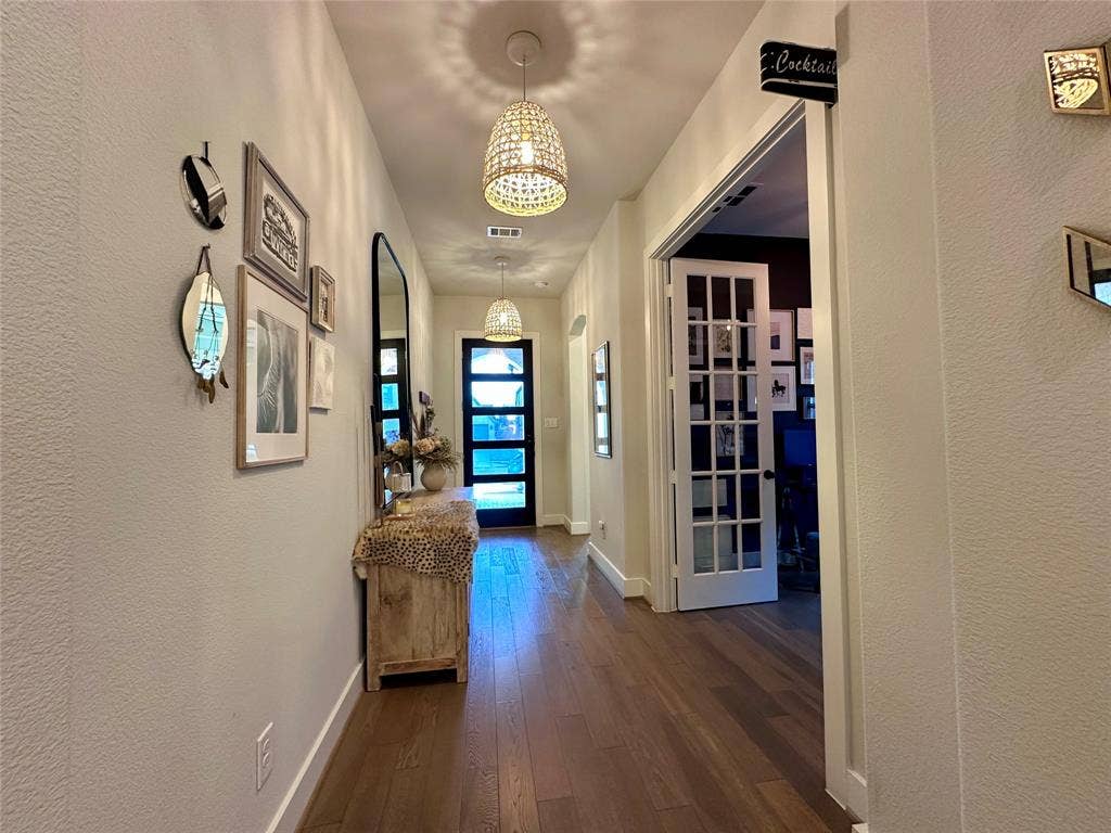 2712 War Admiral Street, Celina, TX 75009 Entryway featuring wood-finish flooring, dual woven pendant light fixtures, and a glass-paneled front door with horizontal grid detailing, complemented by a multi-pane French door