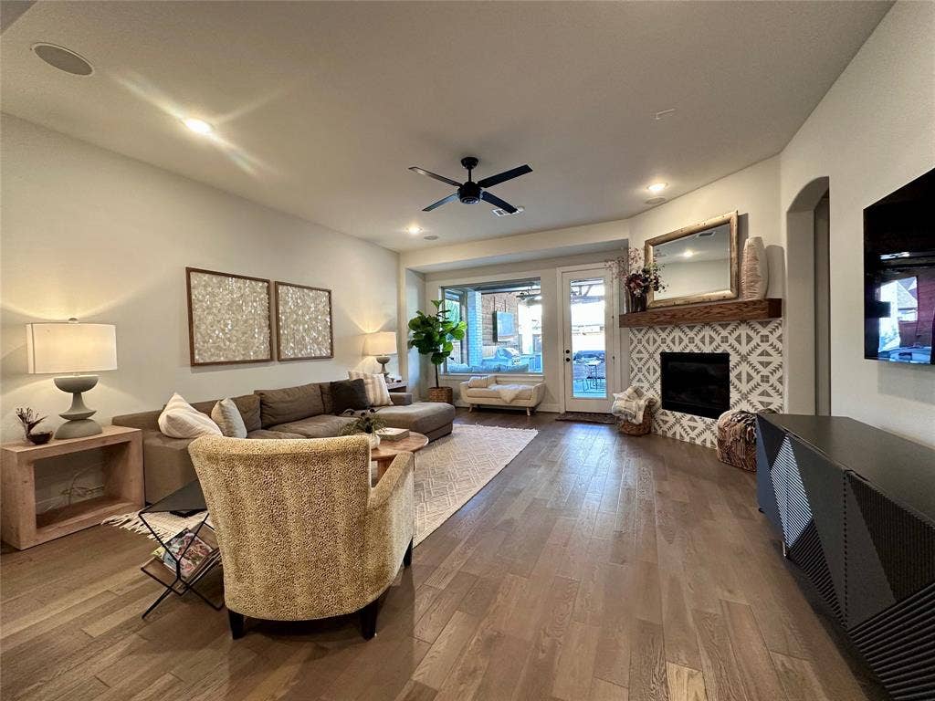 2712 War Admiral Street, Celina, TX 75009 Open-concept living space featuring wood-finish flooring, recessed lighting, ceiling fan, and a fireplace with decorative tile surround and natural wood mantel