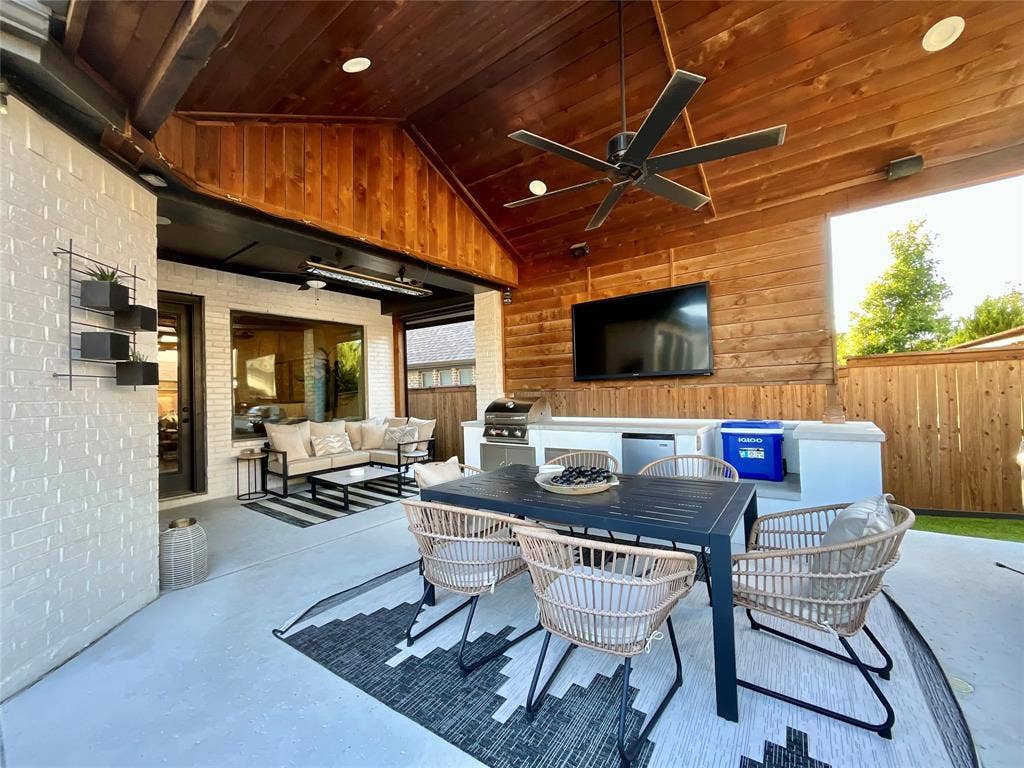 2712 War Admiral Street, Celina, TX 75009 Covered patio featuring a vaulted wood-plank ceiling, recessed lighting, ceiling fan, white brick exterior walls, and a built-in outdoor kitchen with a stone countertop