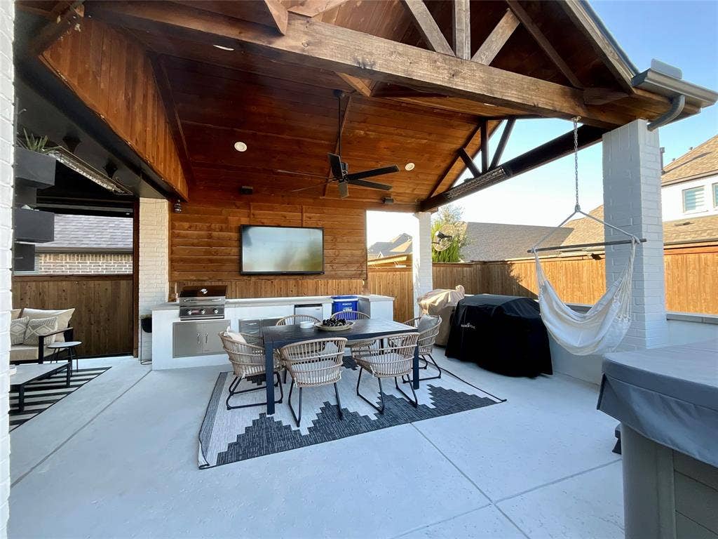2712 War Admiral Street, Celina, TX 75009 Covered patio featuring a vaulted wood-plank ceiling with exposed timber trusses, white brick support pillars, built-in stainless steel outdoor kitchen, and concrete flooring