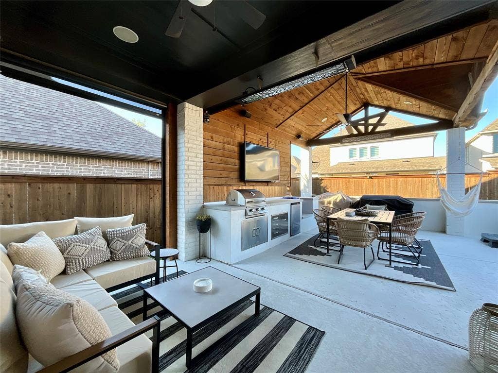 2712 War Admiral Street, Celina, TX 75009 Covered patio featuring a vaulted wood-paneled ceiling, integrated outdoor kitchen with stainless steel appliances, brick-accented wall, and recessed lighting