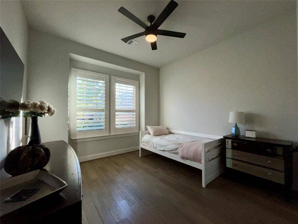 2712 War Admiral Street, Celina, TX 75009 Wood-finish flooring, dual windows with plantation shutters, and a matte black ceiling fan with integrated lighting