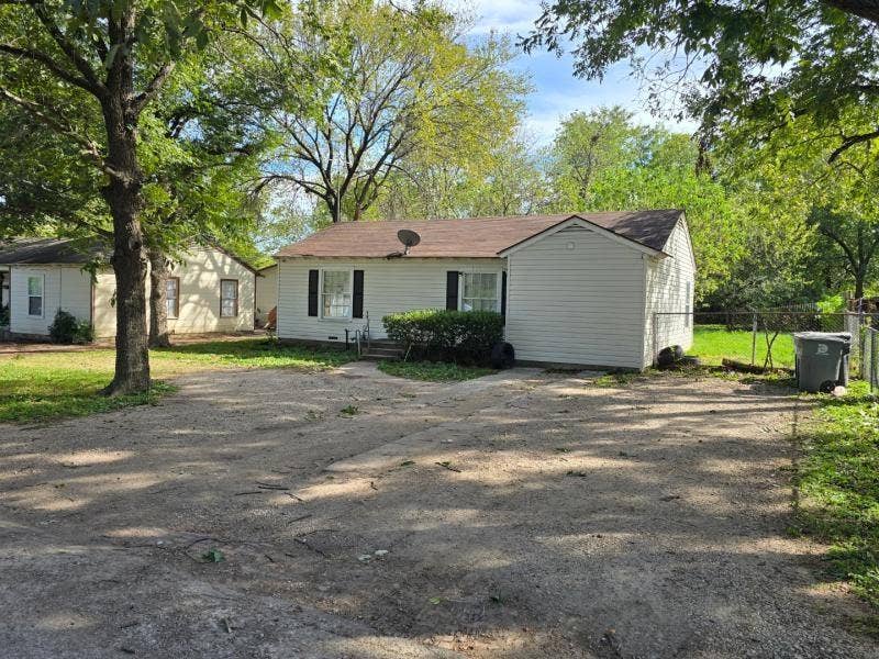 530 Elston Drive, Dallas, TX 75232 Single-story residence with light-colored horizontal siding, asphalt shingle roof, dark decorative shutters, and expansive exterior grounds with mature trees