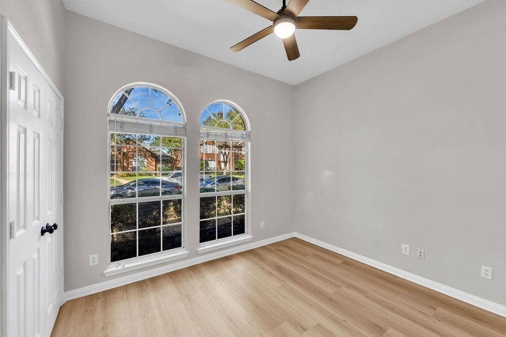12109 Biloxi Drive, Frisco, TX 75035 Room featuring wood-finish flooring, dual arched windows with muntins, and a ceiling-mounted light fixture with fan