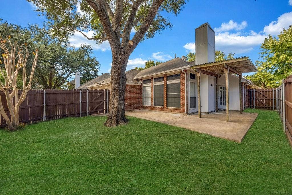 12109 Biloxi Drive, Frisco, TX 75035 Backyard featuring a concrete patio, wood pergola, red brick exterior, chimney, and wooden privacy fencing