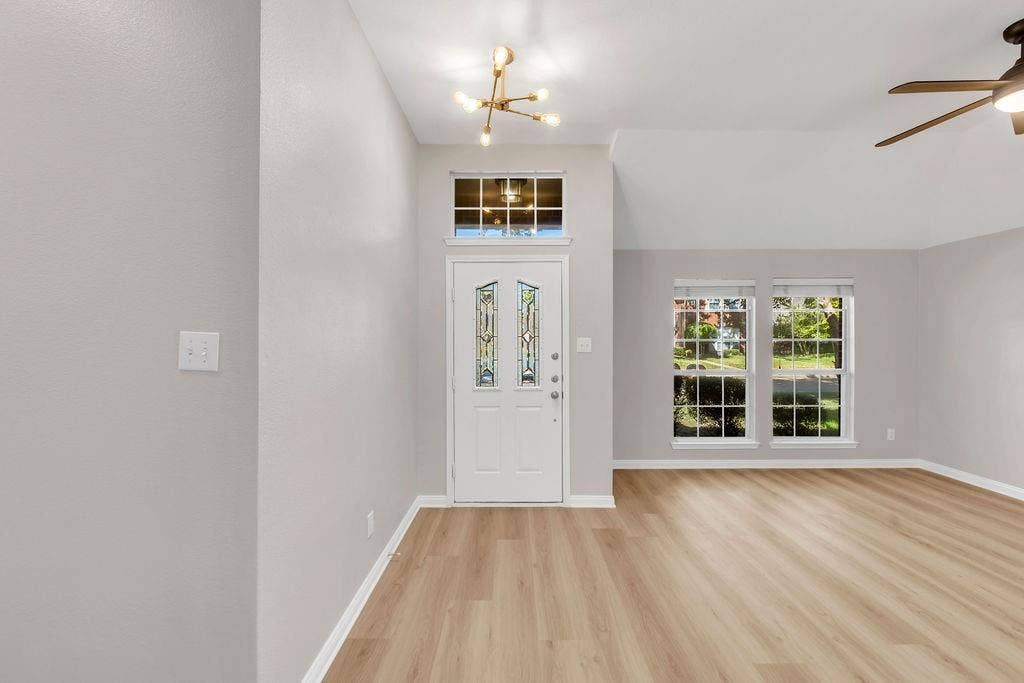 12109 Biloxi Drive, Frisco, TX 75035 Entryway featuring wood-finish flooring, vaulted ceilings, multi-pane windows, a decorative glass-panel front door with a transom window, and a contemporary multi-arm light fixture
