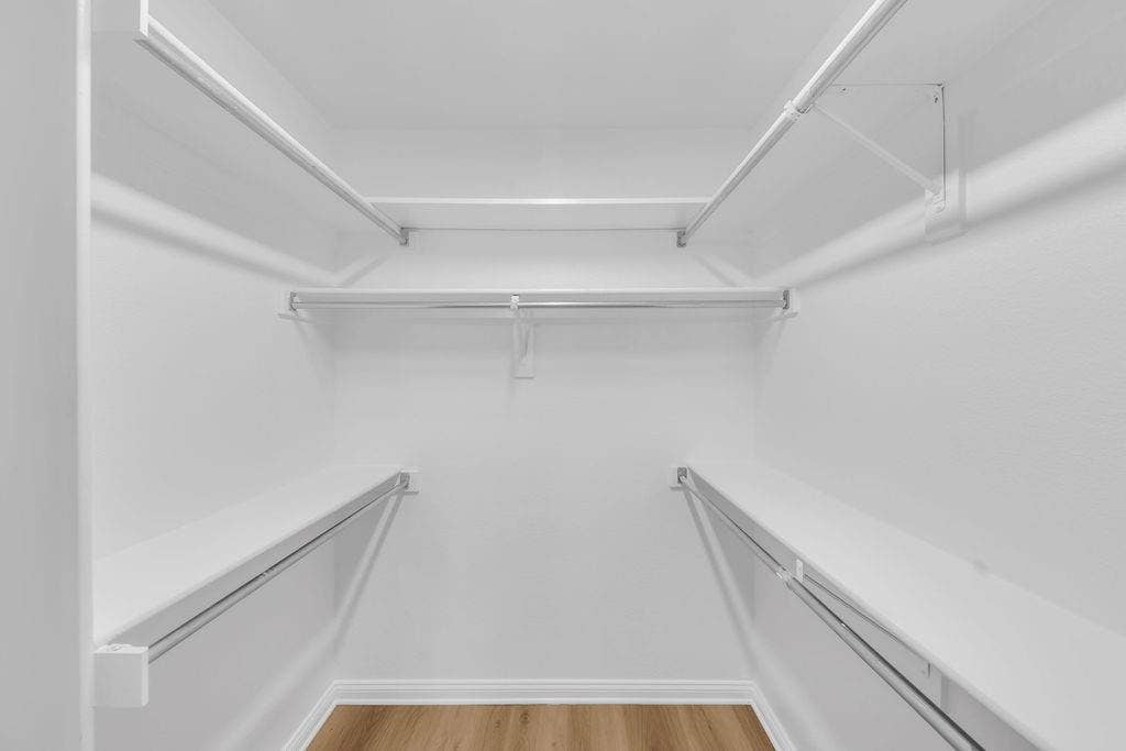 12109 Biloxi Drive, Frisco, TX 75035 Walk-in closet featuring multi-level white shelving and integrated metal hanging rods over wood-finish flooring