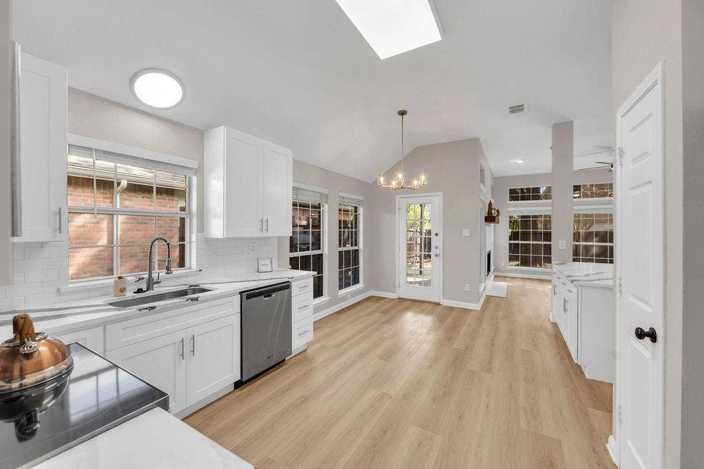 12109 Biloxi Drive, Frisco, TX 75035 Kitchen featuring white cabinetry, wood-finish flooring, vaulted ceilings with recessed lighting, subway tile backsplash, and stainless steel appliances