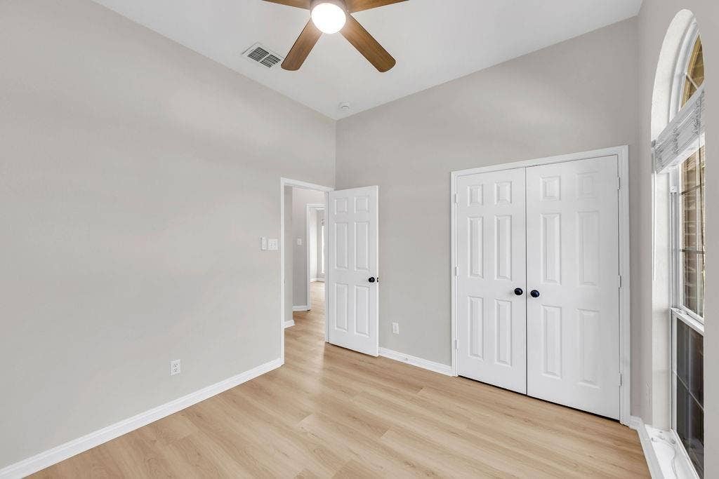 12109 Biloxi Drive, Frisco, TX 75035 Interior space featuring high ceilings, wood-finish flooring, an arched window, and dual-panel closet doors with matte black hardware