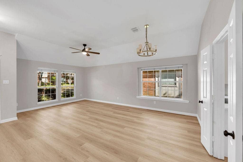 12109 Biloxi Drive, Frisco, TX 75035 Vaulted ceiling featuring a multi-arm chandelier, wood-finish flooring, and multiple windows with grid detailing