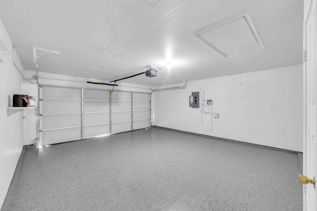 12109 Biloxi Drive, Frisco, TX 75035 Finished garage featuring epoxy flooring, an automatic door opener, and ceiling access hatch
