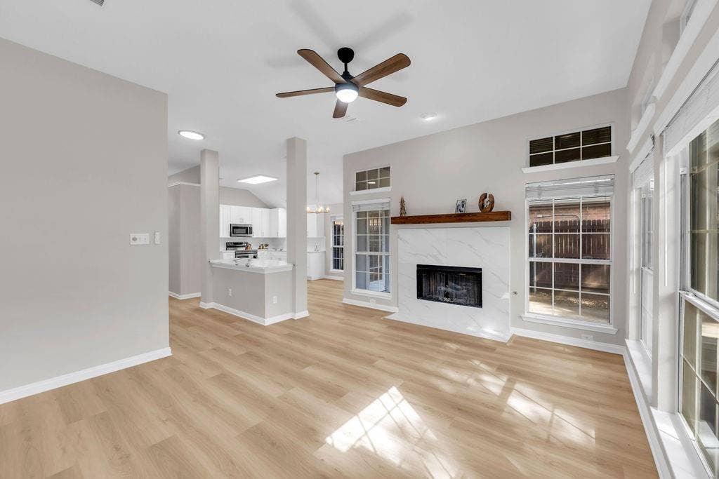 12109 Biloxi Drive, Frisco, TX 75035 Living area featuring wood-finish flooring, a fireplace with a stone-surround facade and wood mantel, recessed lighting, a ceiling fan, and large windows with transom accents