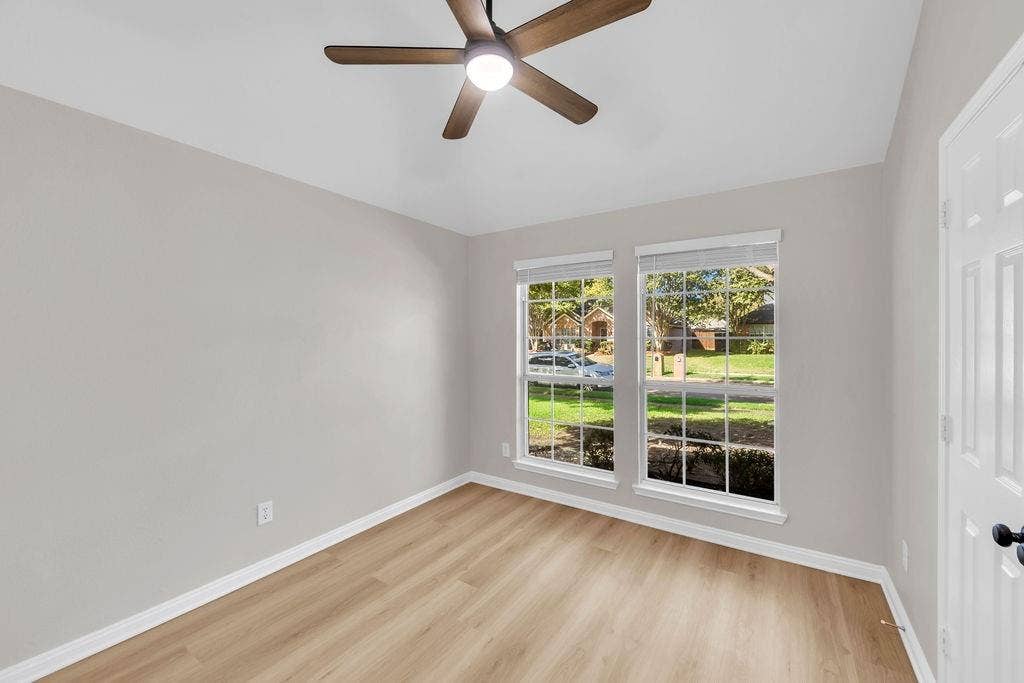 12109 Biloxi Drive, Frisco, TX 75035 Neutral-toned interior featuring wood-finish flooring, a central ceiling fan with integrated lighting, and dual windows with grid detailing