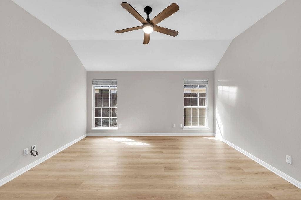 12109 Biloxi Drive, Frisco, TX 75035 Vaulted ceiling with a central multi-blade ceiling fan, wood-finish flooring, and dual windows with grid mullions