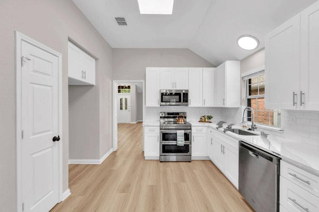 12109 Biloxi Drive, Frisco, TX 75035 Kitchen featuring white Shaker-style cabinetry, stainless steel appliances, white subway tile backsplash, solid-surface countertops, and wood-finish flooring