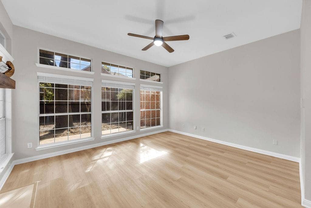12109 Biloxi Drive, Frisco, TX 75035 Living area featuring wood-finish flooring, high ceilings, large windows with transom panels, and a center ceiling fan