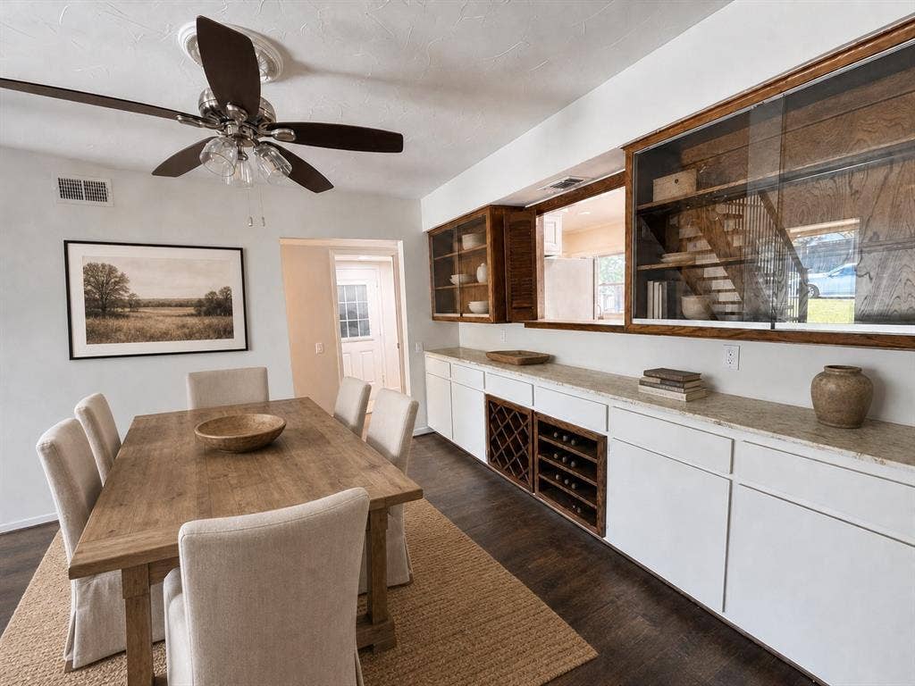 3210 Cortez Court W, Irving, TX 75062 Custom built-in cabinetry featuring glass-front display sections, stone countertop, dedicated wine storage, wood-finish flooring, and a multi-blade ceiling fan with integrated lighting