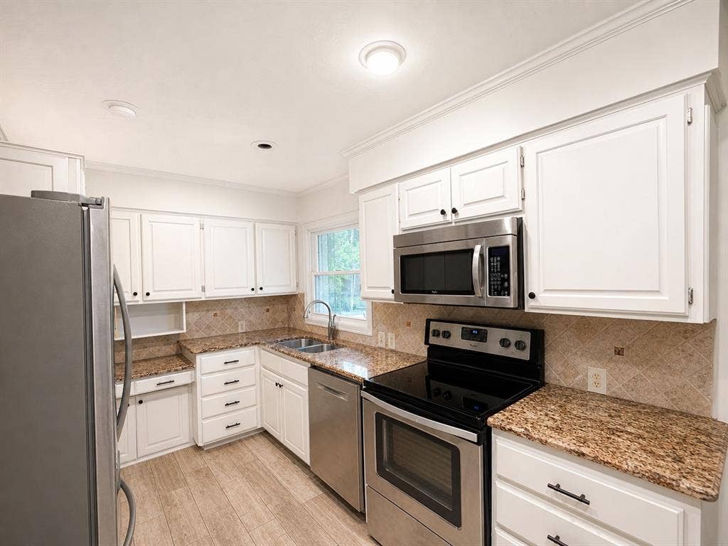 3210 Cortez Court W, Irving, TX 75062 Kitchen featuring white cabinetry, stone-surface countertops, stone tile backsplash, stainless steel appliances, and wood-finish flooring