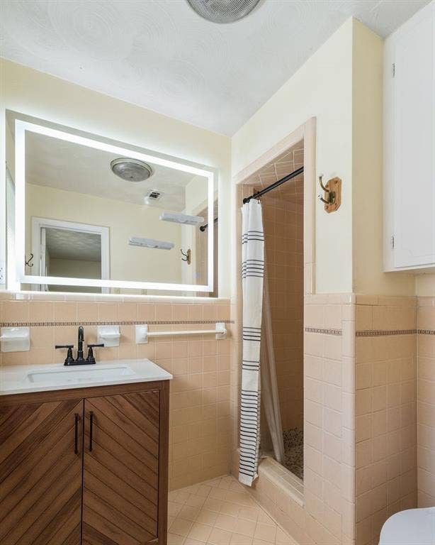 Vanity featuring wood-finish cabinetry with chevron detail, rectangular vessel sink, matte black faucet, and an integrated LED-backlit mirror