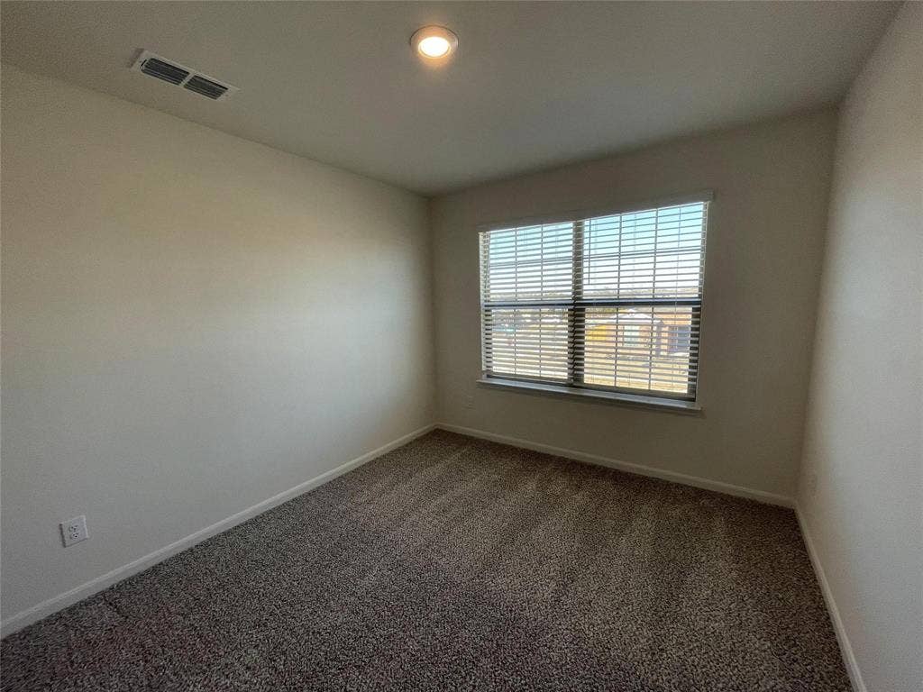 Neutral-toned interior room featuring wall-to-wall carpeting, a multi-pane window with horizontal blinds, and a recessed ceiling light fixture