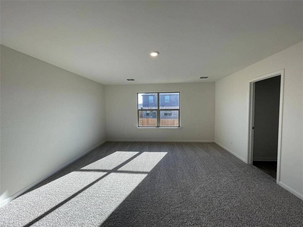 Neutral-toned interior space featuring neutral carpeting, a central recessed light fixture, and a single-pane window with a sill