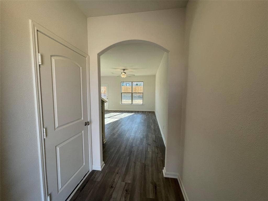 Interior entryway featuring an arched passage, wood-finish flooring, and a two-panel interior door with brushed nickel hardware