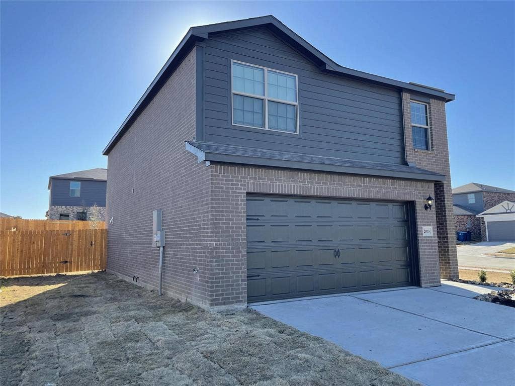 Two-story exterior featuring a brick and horizontal siding façade, a dual-car garage, and a concrete driveway