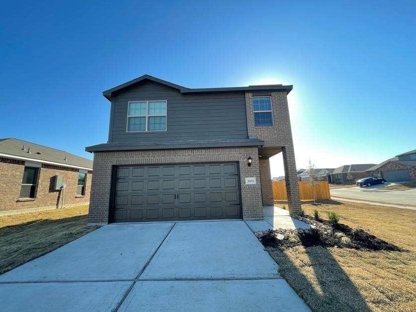 Two-story exterior featuring a brick and horizontal siding facade, an attached two-car garage, and a concrete driveway