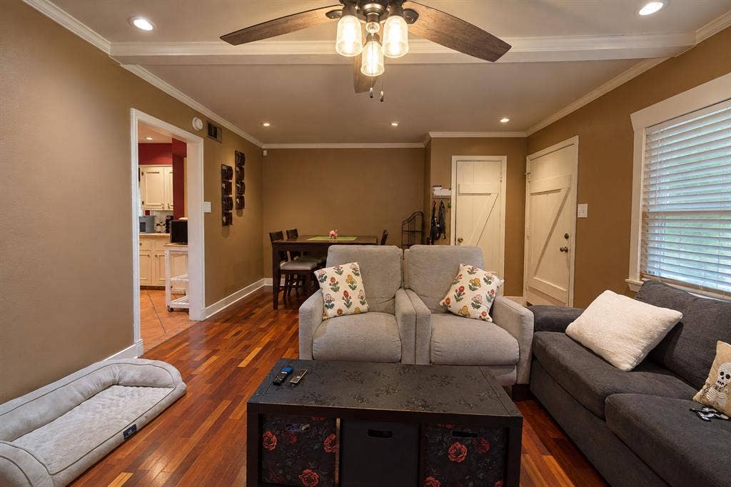Living area featuring polished wood-finish flooring, recessed lighting, crown molding, and a central ceiling fan with integrated lighting