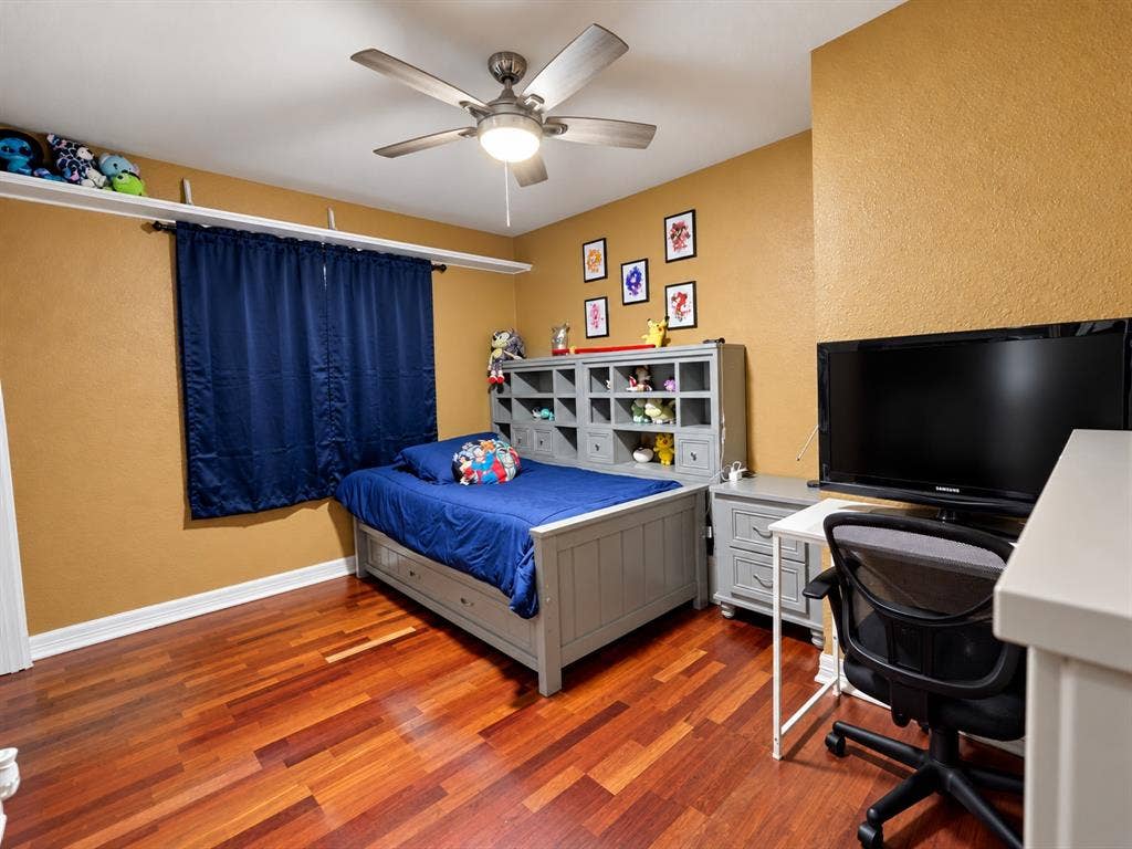 Wood-finish flooring, ceiling fan with integrated lighting, and wall-mounted shelving