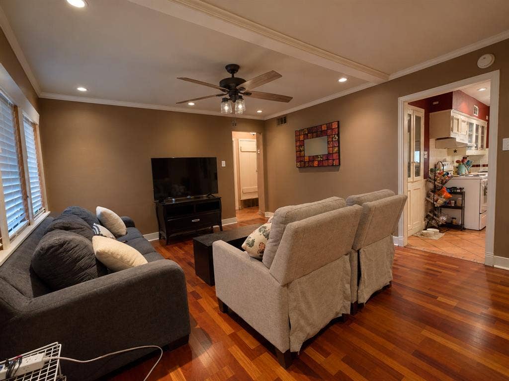 Wood-finish flooring, recessed lighting, and a central ceiling fan with integrated lighting