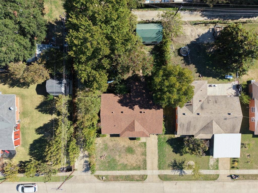 Aerial perspective of the property featuring a shingled roof, concrete driveway, and mature landscaping