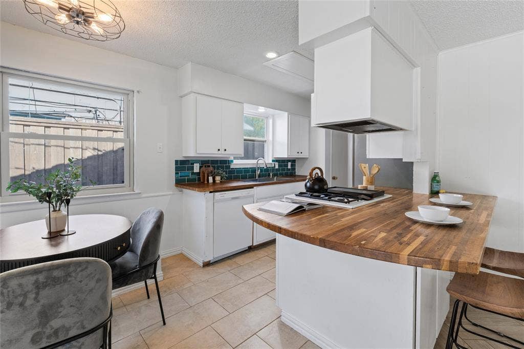 907 Crest Park Drive, Garland, TX 75042 Kitchen featuring wood-finish countertops, white cabinetry, dark blue tile backsplash, gas cooktop, and tile flooring
