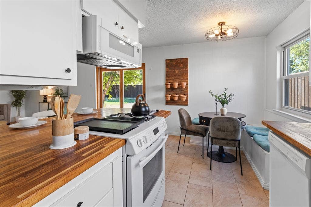907 Crest Park Drive, Garland, TX 75042 Kitchen featuring wood-finish countertops, white cabinetry, a built-in microwave, tile flooring, and a sliding glass door