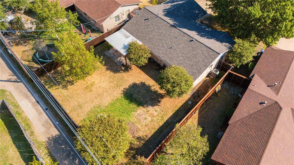 907 Crest Park Drive, Garland, TX 75042 Aerial perspective of a fenced backyard featuring a covered patio, mature trees, and a shingle-roof structure