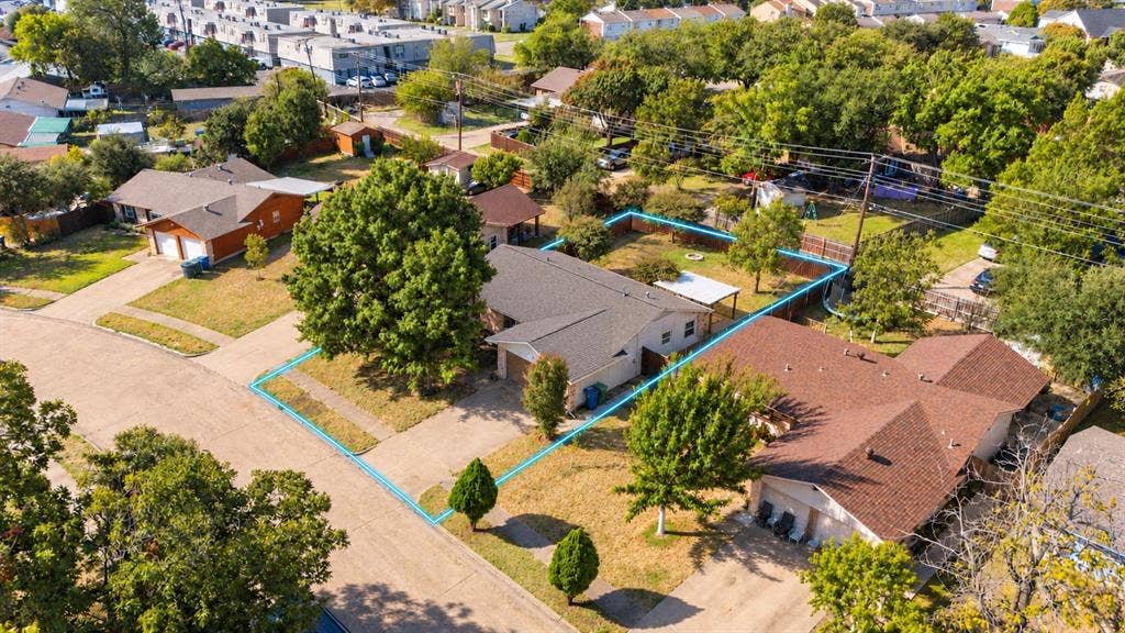 907 Crest Park Drive, Garland, TX 75042 Aerial view of a residential property featuring a composition shingle roof, concrete driveway, attached garage, fenced rear yard, and mature tree landscaping