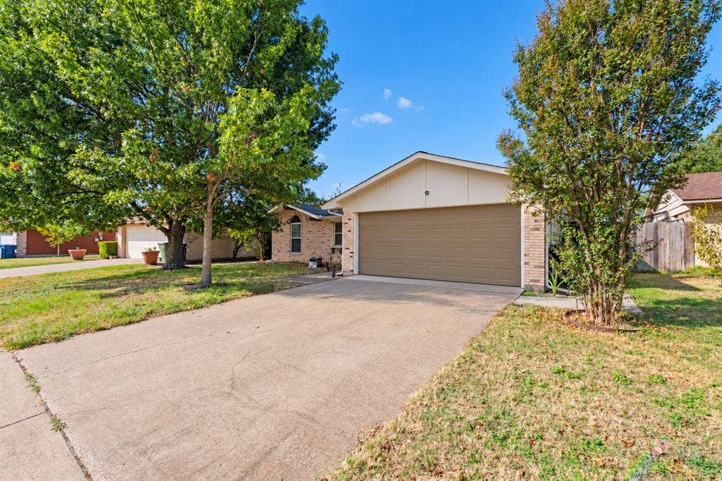 907 Crest Park Drive, Garland, TX 75042 Single-story exterior featuring a brick facade, gabled roofline, two-car garage, and concrete driveway