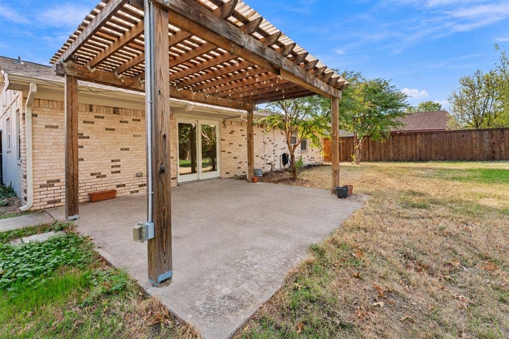 907 Crest Park Drive, Garland, TX 75042 Backyard patio featuring a wood-beam pergola, concrete flooring, brick exterior siding, and a wooden privacy fence