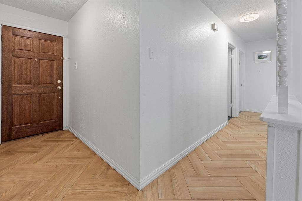 907 Crest Park Drive, Garland, TX 75042 Entryway featuring a wood-finish door, herringbone-pattern wood-finish flooring, and a decorative white painted baluster