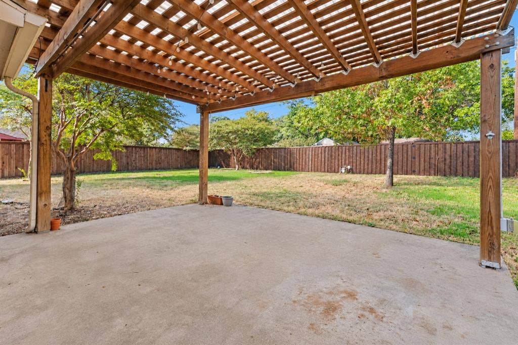 907 Crest Park Drive, Garland, TX 75042 Covered patio featuring a wooden pergola, concrete flooring, and a fenced backyard with mature trees
