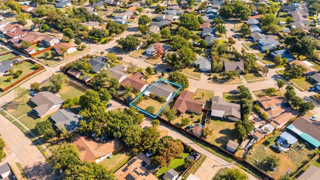 907 Crest Park Drive, Garland, TX 75042 Aerial perspective of a residential property featuring a pitched roofline, an attached garage, a defined lot boundary, and established perimeter trees